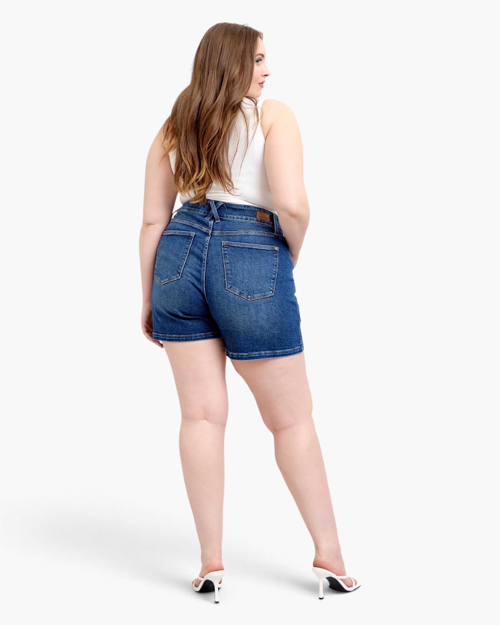 Beach Rose Co. dark wash denim shorts with crossed back belt loops and patch pockets worn by a model from behind