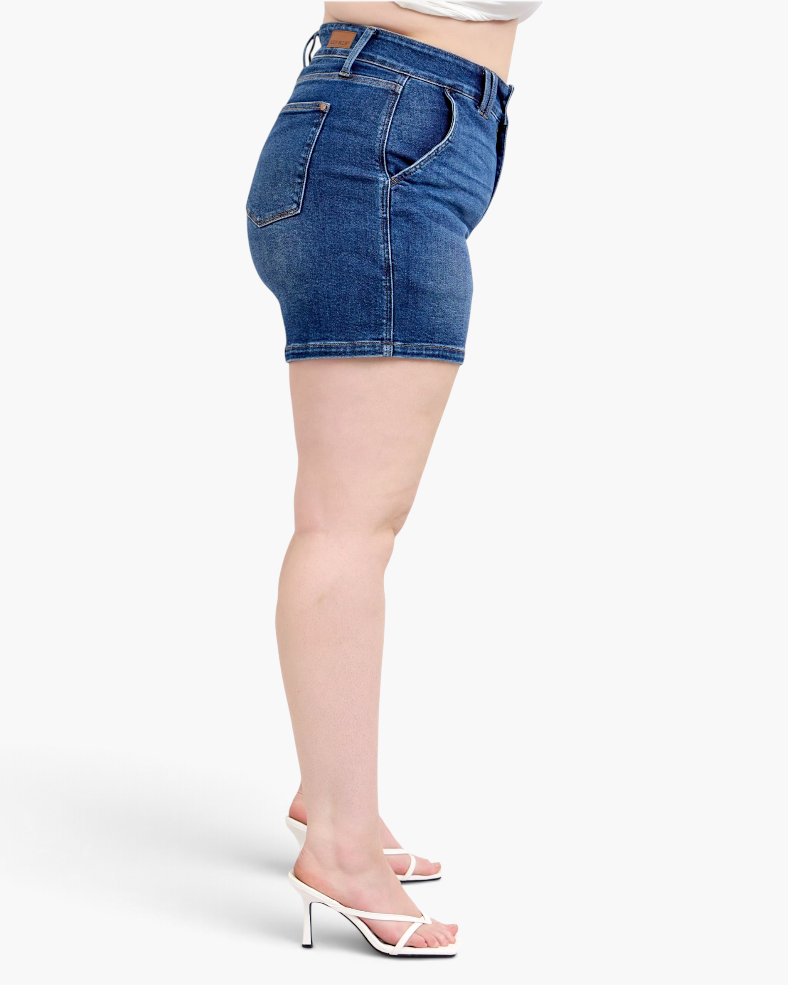 Beach Rose Co. dark wash denim shorts with a wide waistband, double-button closure, and curved pockets, side view.