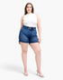 Beach Rose Co. dark wash denim shorts with a wide double-button waistband worn by a model in a white tank top.