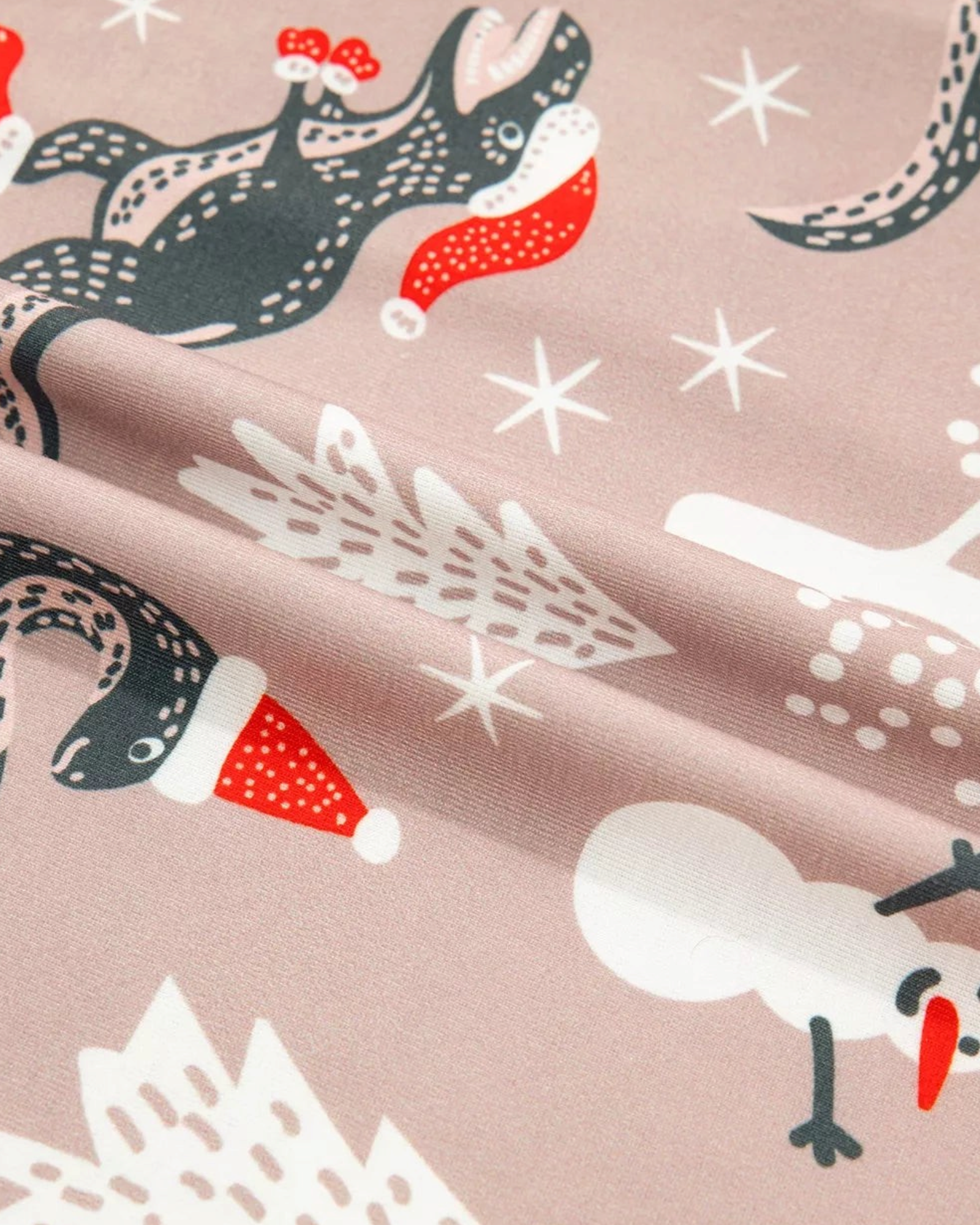 Beach Rose Co. taupe pajama fabric with charcoal dinosaurs wearing Santa hats, snowmen, and festive white trees.
