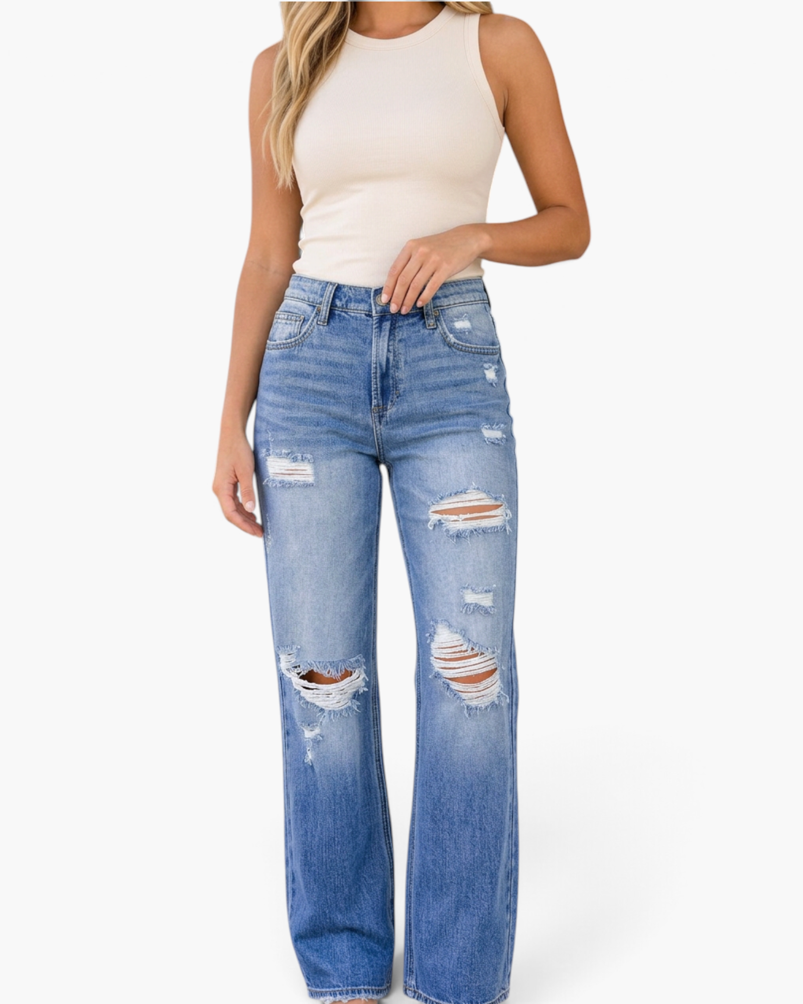 Beach Rose Co. medium wash distressed mid-rise straight leg jeans with frayed rips on a model wearing a beige tank top