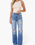 Beach Rose Co. medium wash distressed mid-rise straight leg jeans with frayed rips on a model wearing a beige tank top