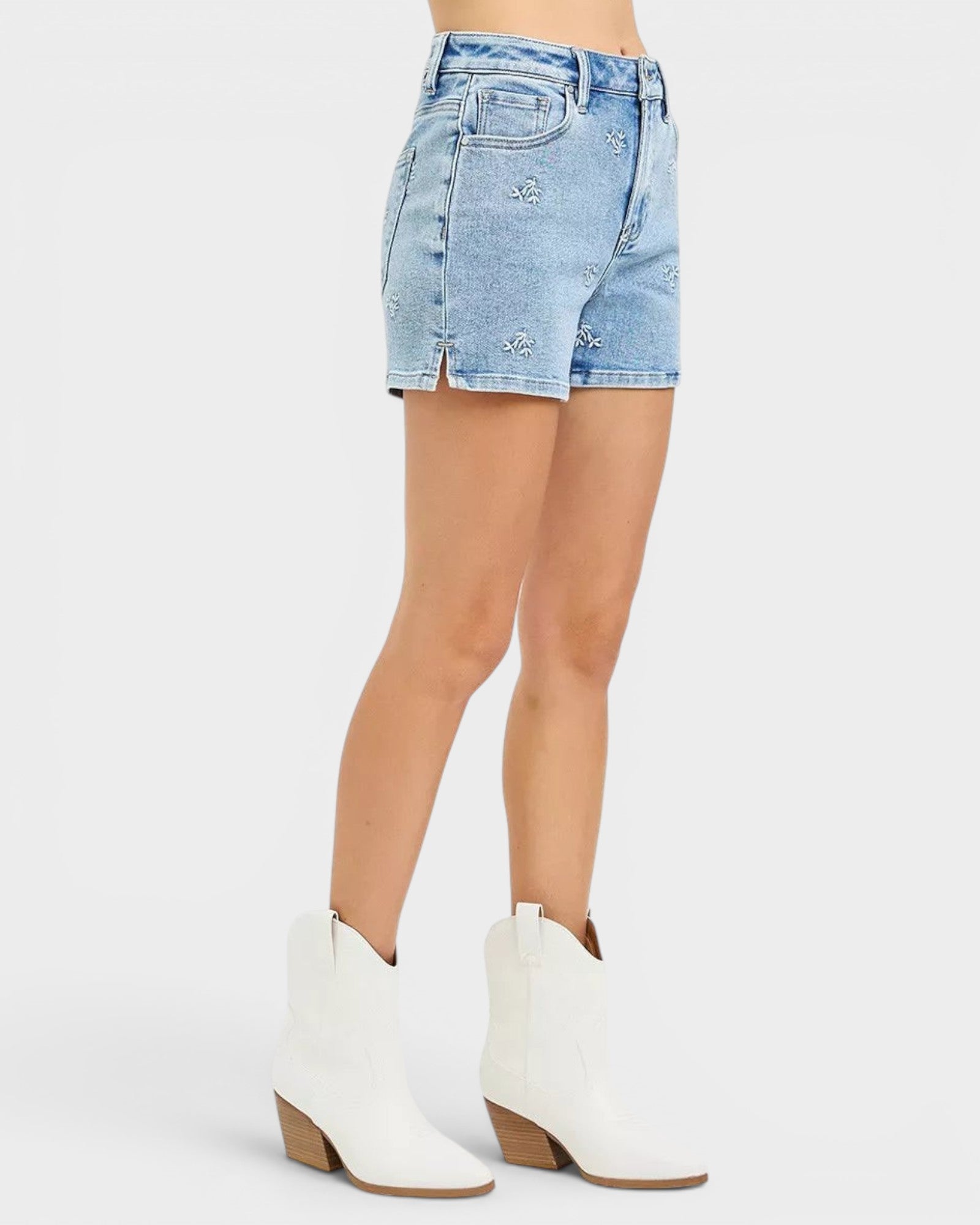 Beach Rose Co. light wash denim shorts with white embroidered floral details, high-rise fit, and short length.