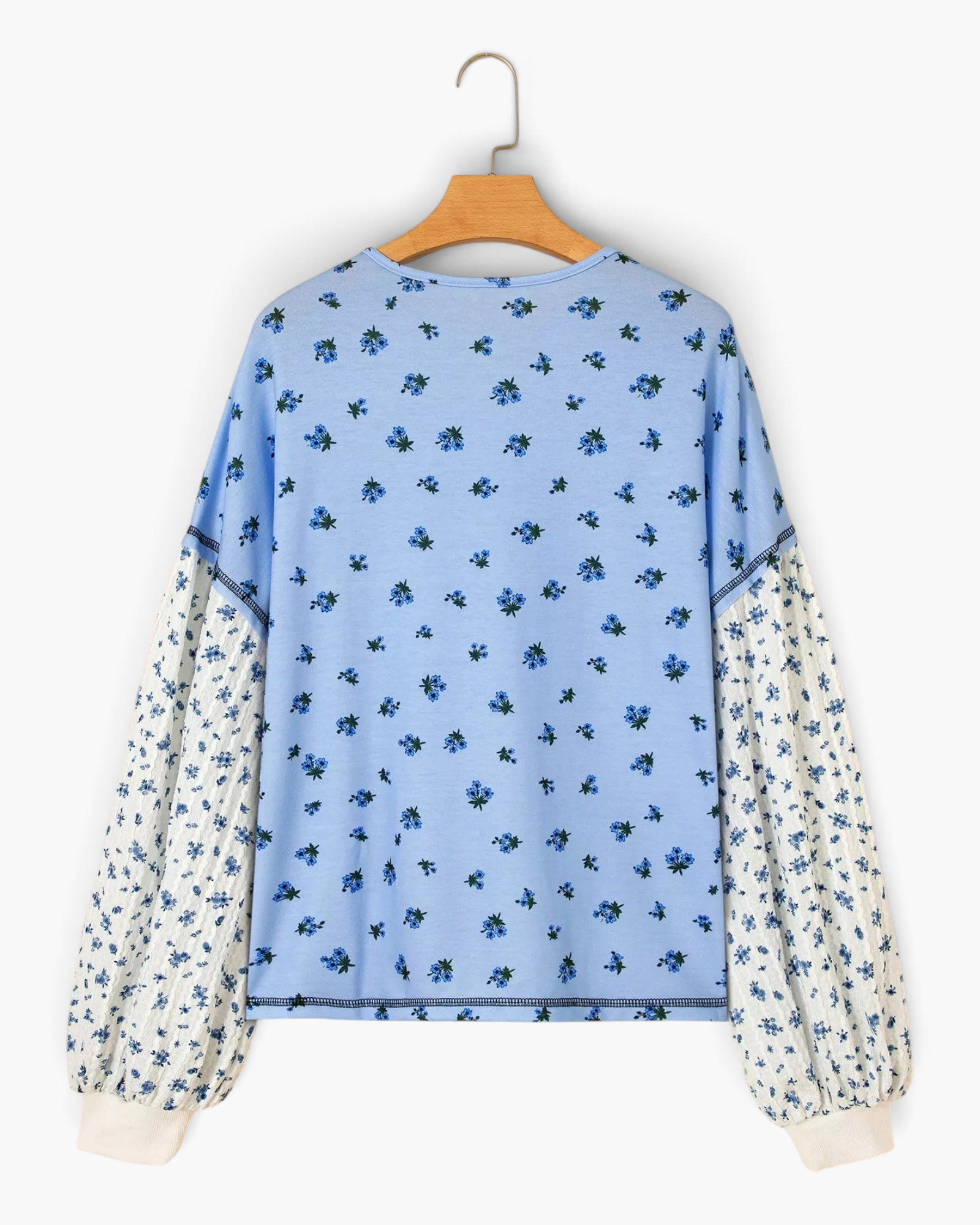 Beach Rose Co. blue floral print long sleeve top with contrasting patterned sleeves and buttoned cuffs.