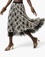 Beach Rose Co. black midi skirt with white floral embroidery and a sheer black tulle hem on a model in motion.