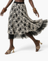 Beach Rose Co. black midi skirt with white floral embroidery and a sheer black tulle hem on a model in motion.