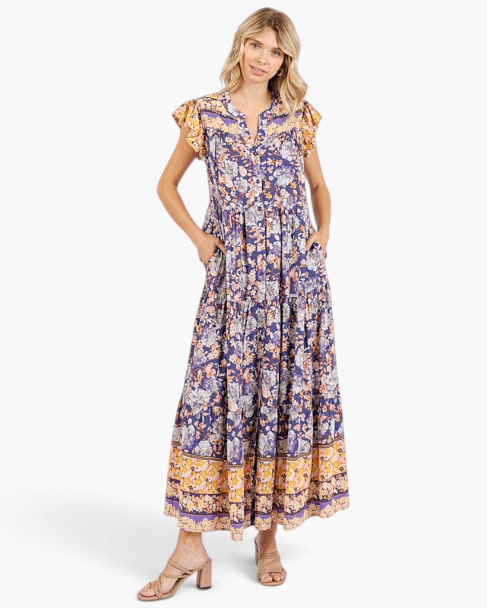 Beach Rose Co. peacock blue floral maxi dress with flutter sleeves, tiered silhouette, and pockets on a model.