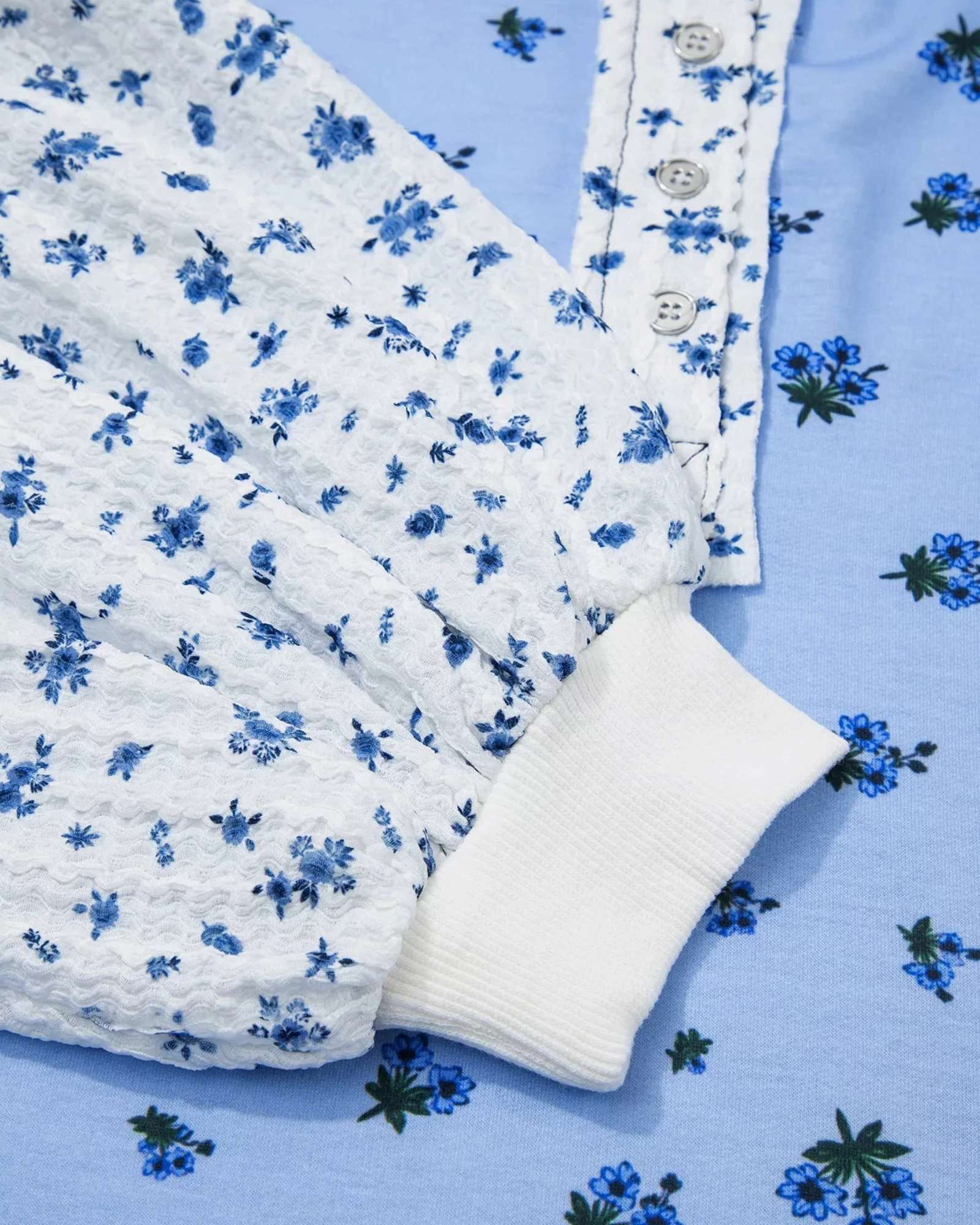 Beach Rose Co. floral print long sleeve top with buttoned contrast detail and ribbed cuffs in blue and white.