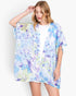 Beach Rose Co. floral print cover-up in blue and purple, worn by a blonde model over a white top against a white background