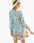 Beach Rose Co. light blue floral viscose dress with long sleeves, V-neck, and straw hat on a model, back view