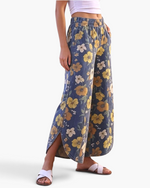 Beach Rose Co. blue wide leg pants featuring a yellow and cream floral print, elastic waist, and curved side slits.