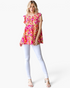 Beach Rose Co. fuchsia floral tiered top with flutter sleeves and a relaxed fit worn with white skinny jeans.