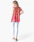 Beach Rose Co. fuchsia floral tiered top with flutter sleeves worn by a model from the back view with white leggings.
