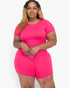 Beach Rose Co. plus size fuchsia short sleeve crop top and shorts set on a model with long blonde-highlighted hair.