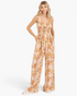Beach Rose Co. ginger floral wide-leg jumpsuit with a smocked waist, gathered bodice, and pockets on a blonde model.