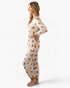 Beach Rose Co. cream gingerbread print pajama set with long sleeve buttoned top and joggers on a smiling woman