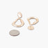 Beach Rose Co. gold-tone abstract teardrop earrings with a polished shiny finish shown next to a US quarter coin.