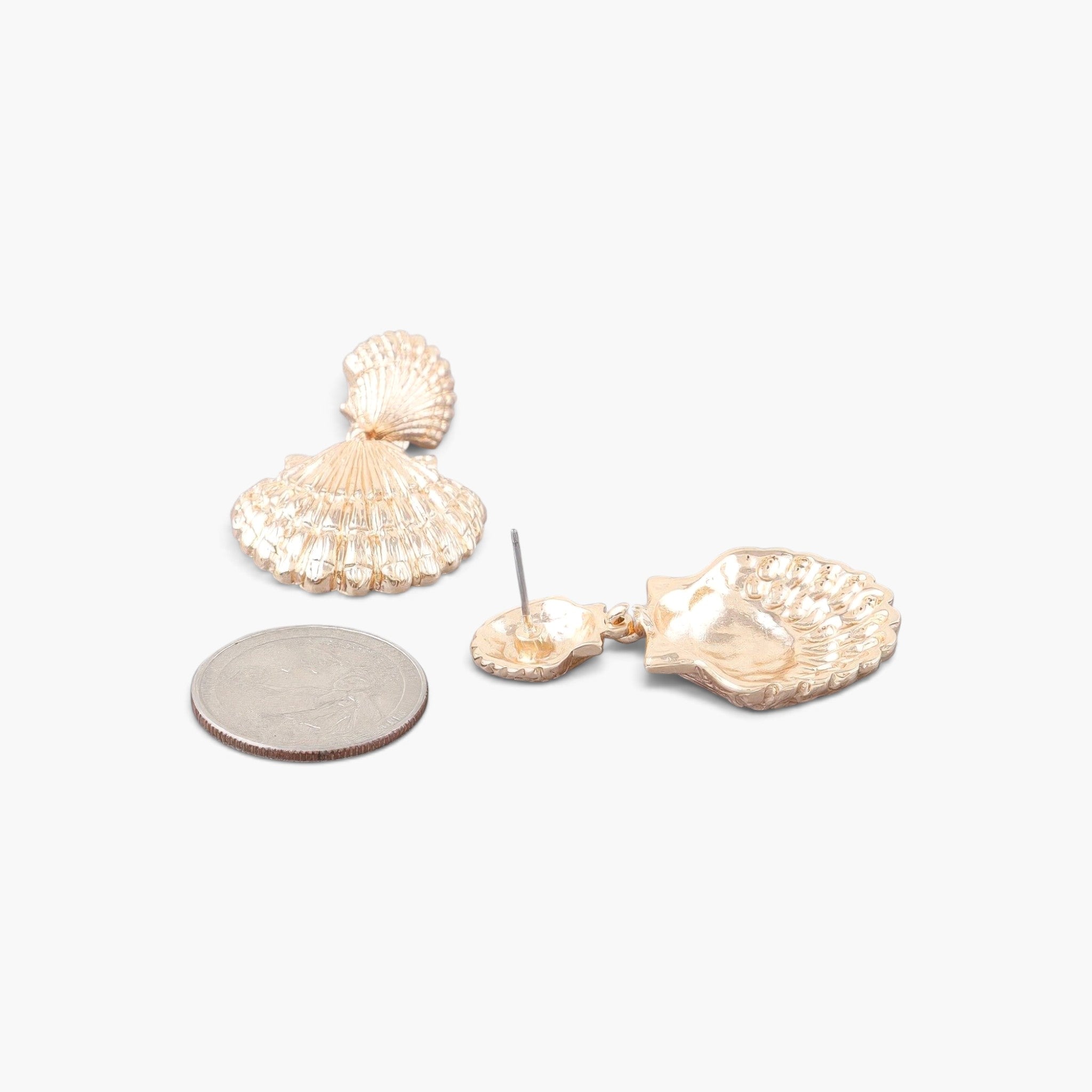 Beach Rose Co. gold double clamshell drop earrings with intricate shell texture shown next to a US quarter for scale.