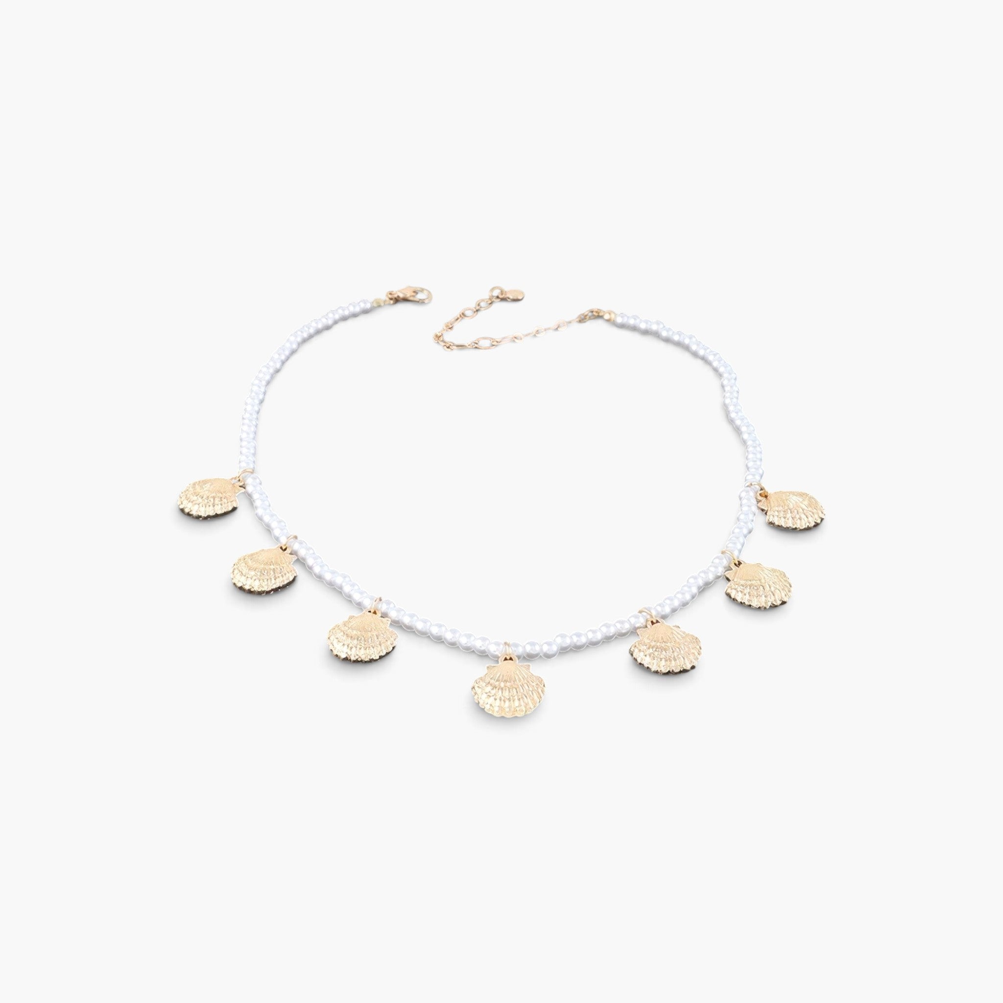 Beach Rose Co. gold clamshell charm necklace featuring a delicate strand of white pearls on a light background.