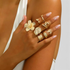 Beach Rose Co. 18K gold-plated ring set featuring sculptural flower, shell, and starfish designs on a model's hand.