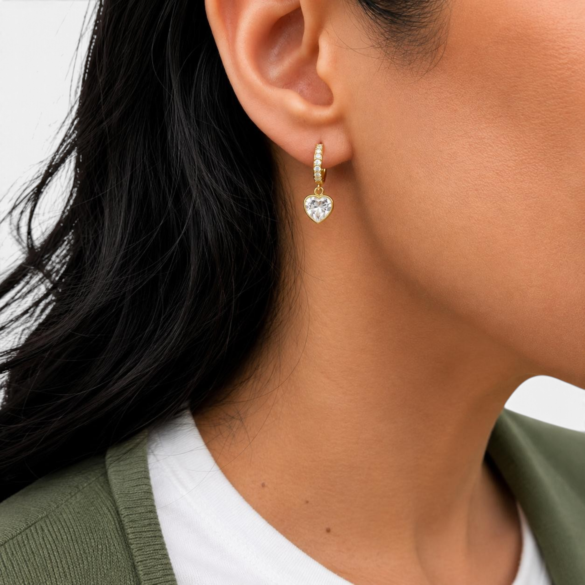 Beach Rose Co. gold huggie earrings with a sparkling cubic zirconia heart charm worn on a model's ear