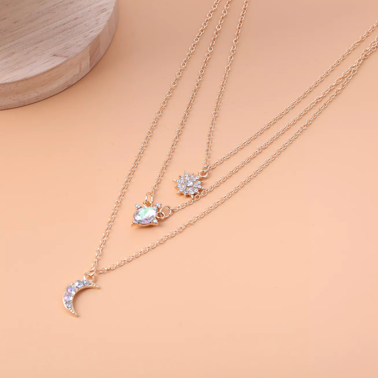 Beach Rose Co. 18K gold-plated layered necklace featuring a zircon sun, teardrop crystal, and crescent moon pendants.
