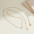Beach Rose Co. 18K gold-plated lariat necklace featuring white synthetic pearls, mixed chains, and a round disc charm.