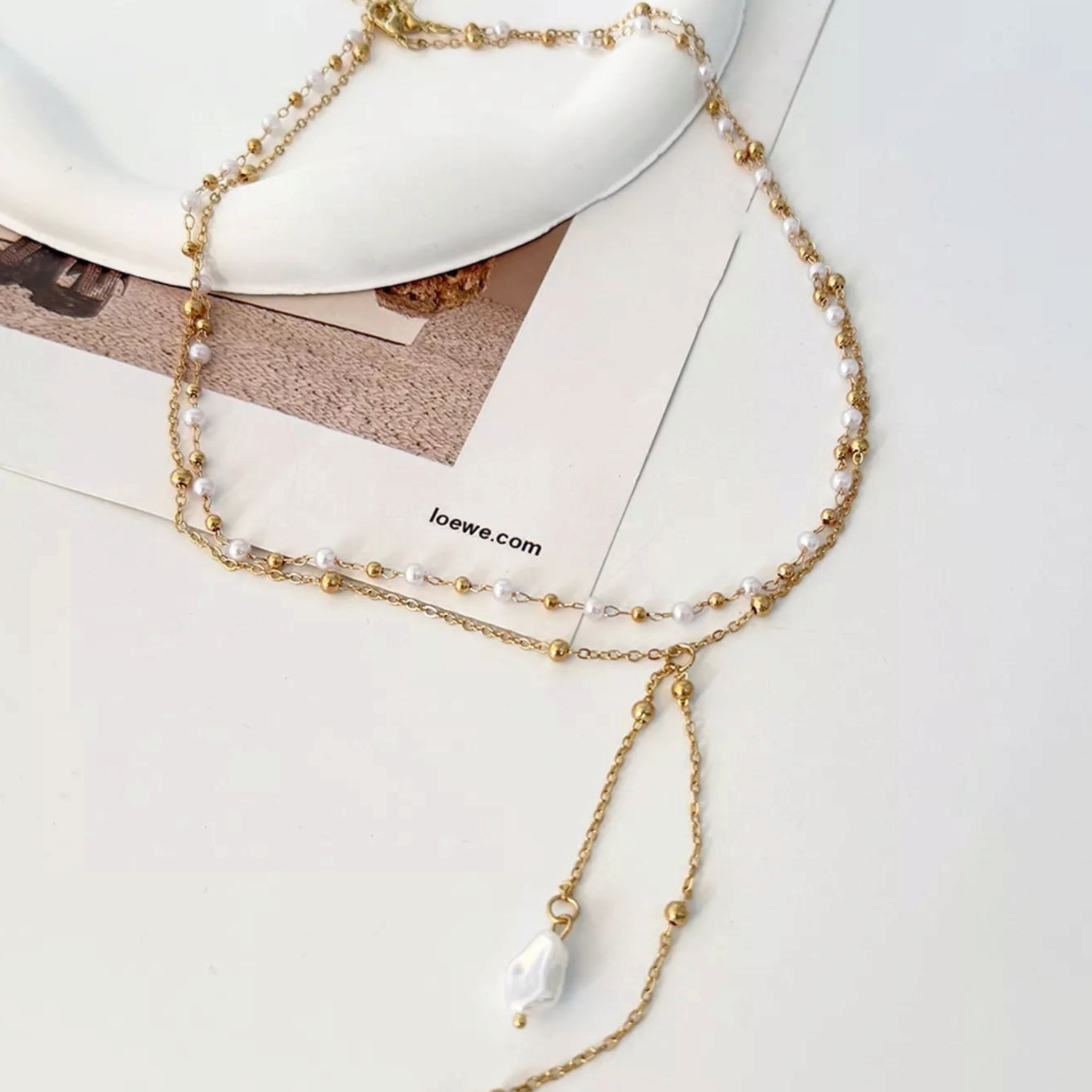 Beach Rose Co. 18K gold-plated layered necklace featuring white faux pearls and delicate gold bead-accented chains.