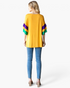 Beach Rose Co. gold top with purple and green color-block layered ruffle sleeves worn with blue jeans, back view.