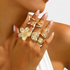 Beach Rose Co. 18K gold-plated ring set featuring sculptural flower, shell, and starfish designs on a woman's hand.