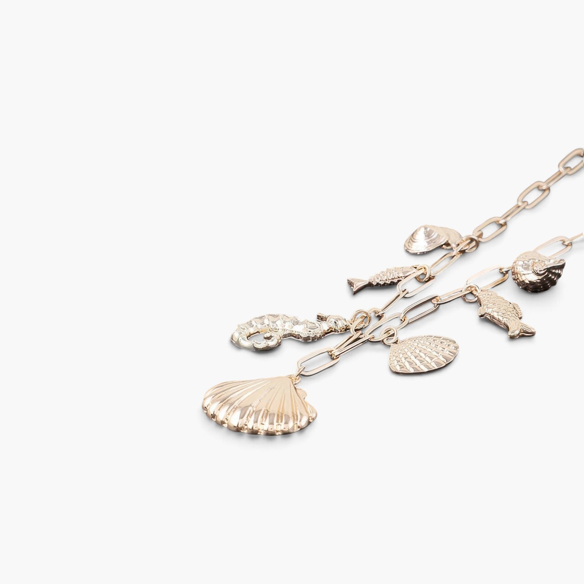 Beach Rose Co. gold chain necklace featuring delicate sea-themed charms including seashells, a seahorse, and fish.