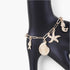 Beach Rose Co. gold chain bracelet featuring dangling starfish, seashell, and fish charms on a black display stand.