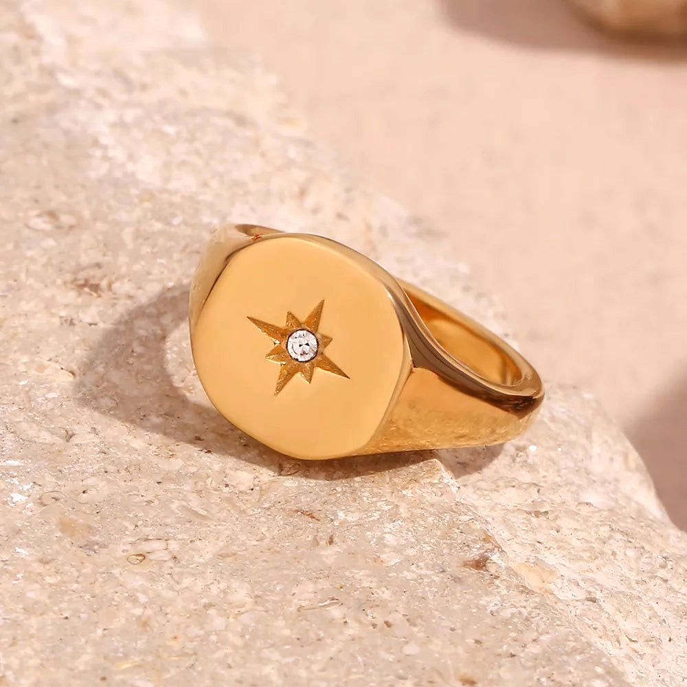 Beach Rose Co. gold-plated signet ring featuring an engraved starburst design with a clear zircon center stone.