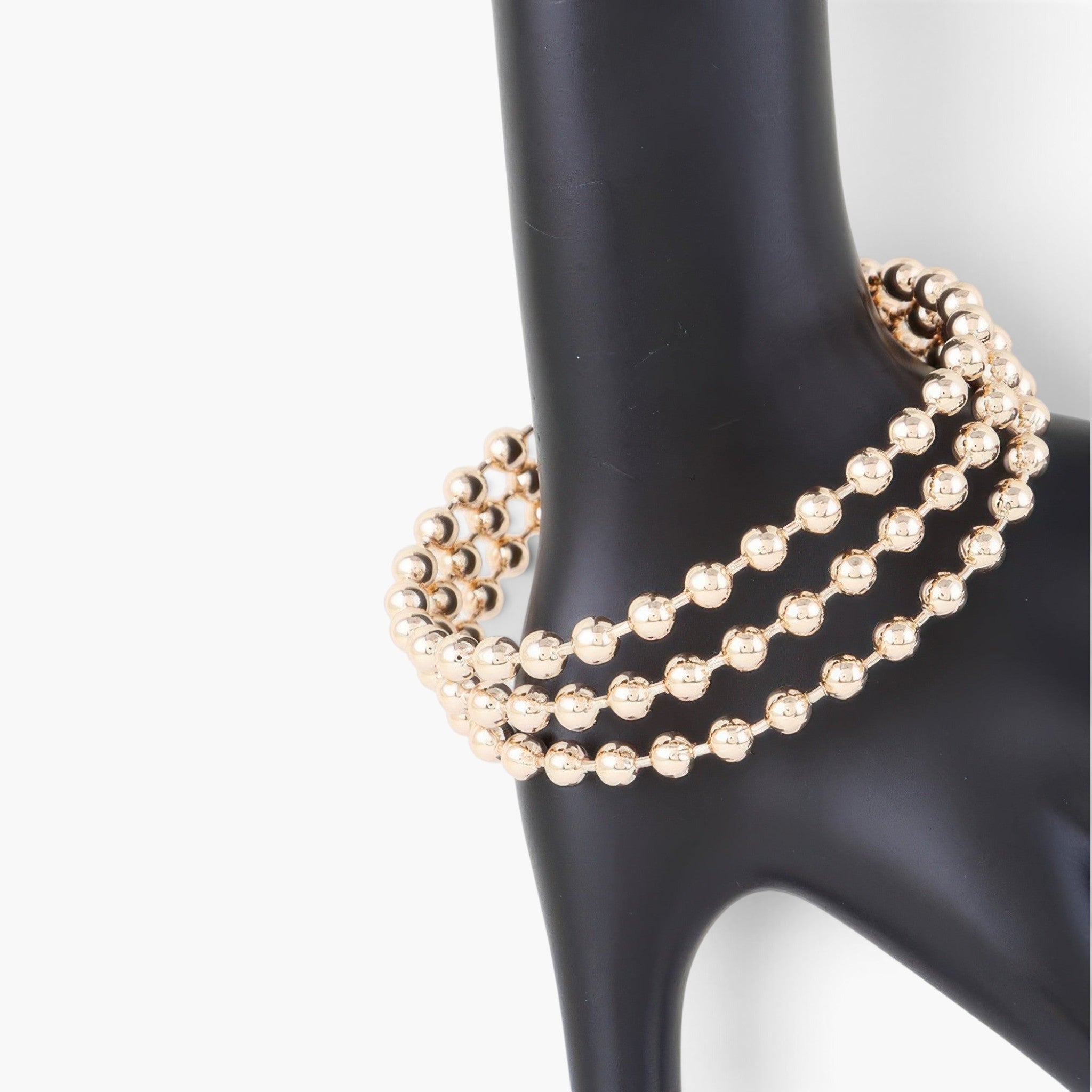 Beach Rose Co. wide triple beaded cuff bracelet in polished gold on a black display stand