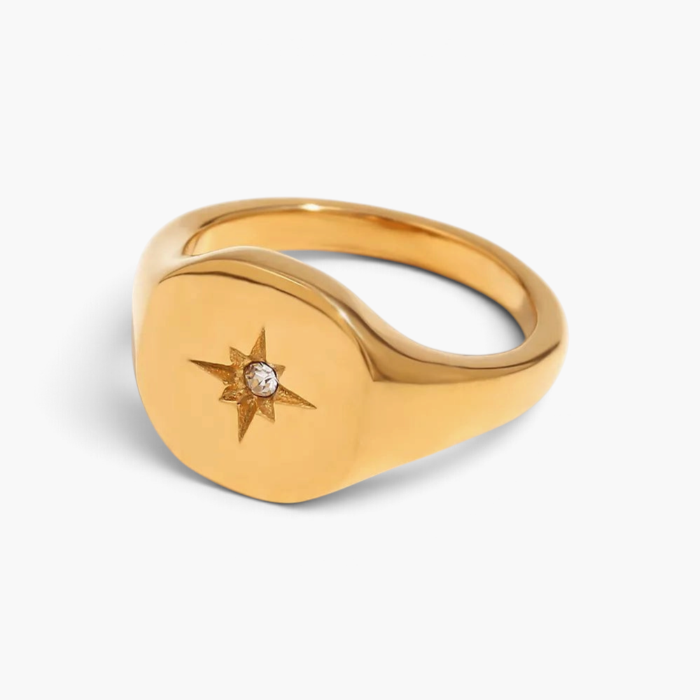 Beach Rose Co. gold-plated signet ring with a polished finish, engraved starburst, and a clear zircon centerpiece.