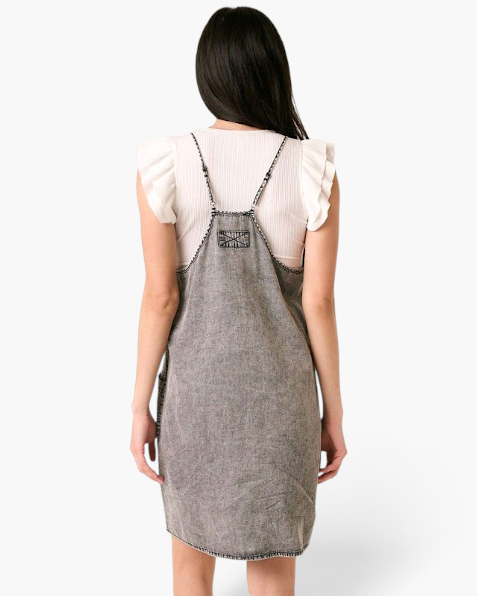 Beach Rose Co. gray washed denim overall dress with racerback straps and contrast stitching worn over a white top