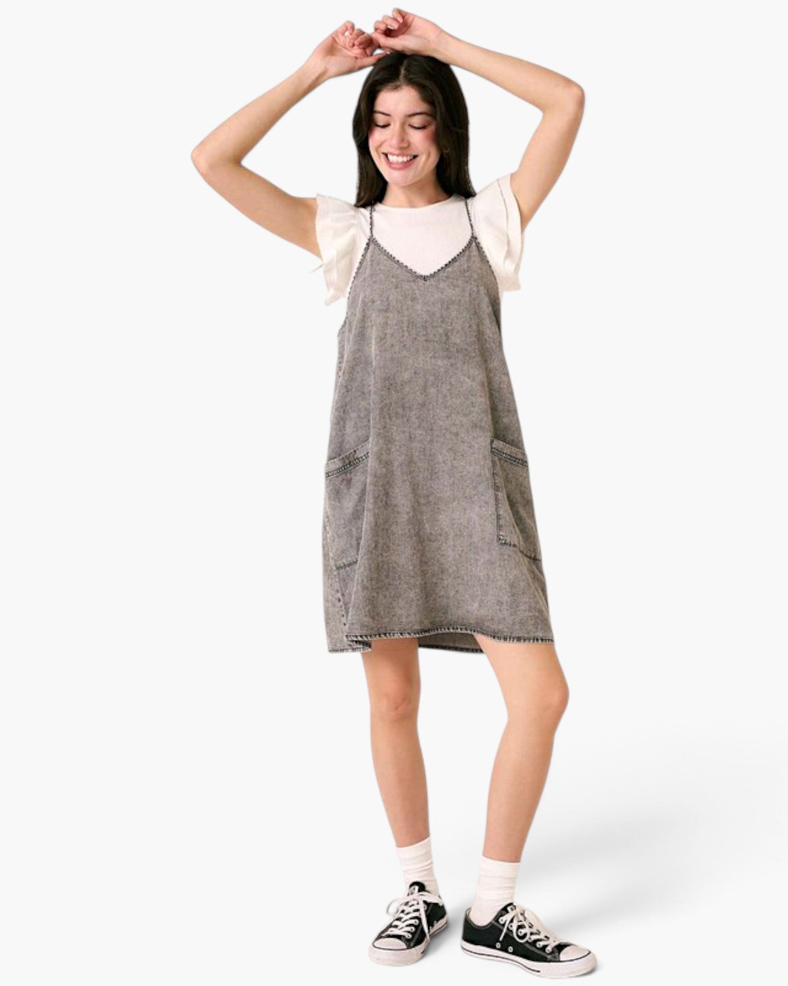 Beach Rose Co. gray washed denim overall dress with oversized pockets and slender straps worn over a white top