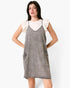 Model wearing a Beach Rose Co. gray washed denim overall dress with oversized pockets over a white flutter-sleeve top.