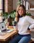 Beach Rose Co. light gray mock neck sweatshirt with navy polka dot trim worn by a woman holding a mug at a desk.