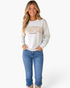 Beach Rose Co. gray crewneck sweatshirt with Pumpkin Season floral graphic worn by a smiling woman with blue jeans.