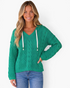 Beach Rose Co. green cable knit V-neck hooded sweater with contrasting drawstrings worn by a smiling blonde model.