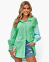 Beach Rose Co. green color block button down blouse with cuffed sleeves worn by a smiling woman with denim shorts