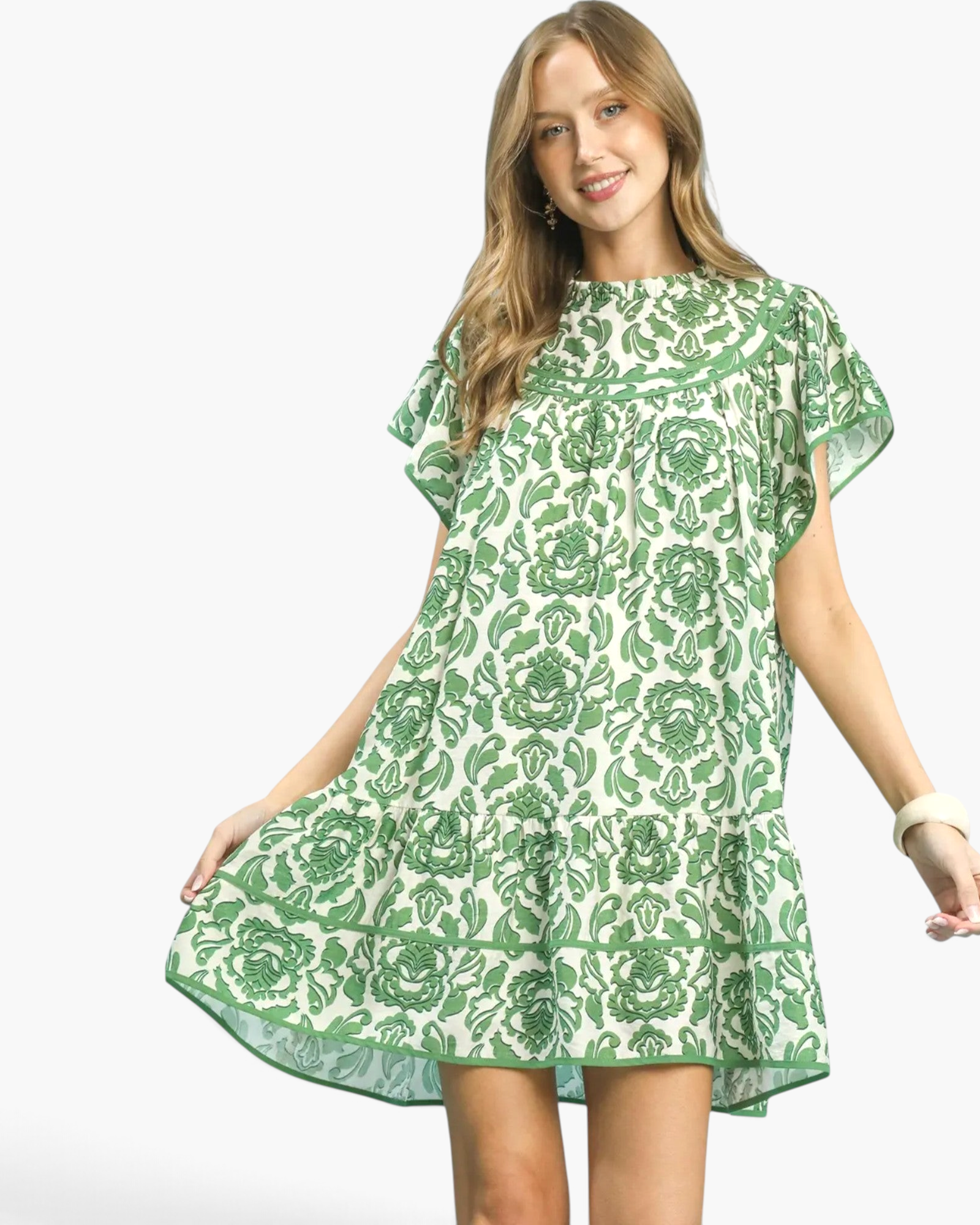 Beach Rose Co. green and cream floral mini dress with flutter sleeves, ruffled neckline, and flounced hem on a model.