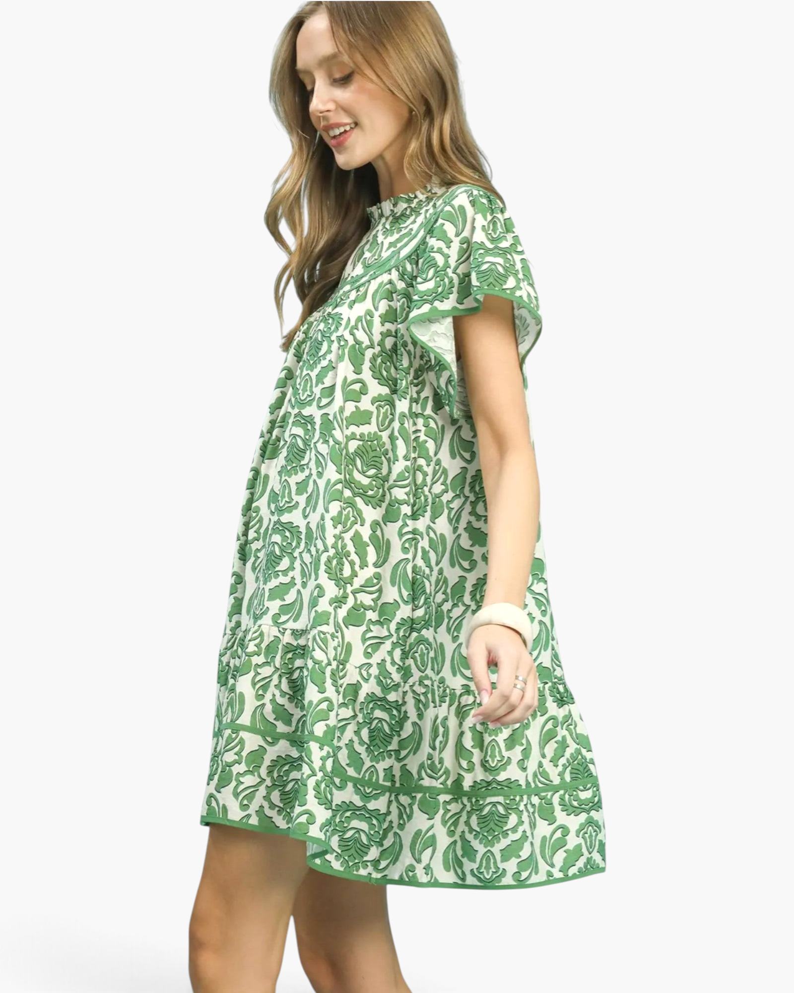 Beach Rose Co. green and cream floral mini dress with flutter sleeves, ruffled neckline, and flounced hem on model.