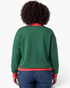 Back view of a model wearing a Beach Rose Co. green sweatshirt with red and white polka dot trim on cuffs and hem.
