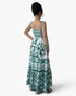 A woman shown from the back wearing a sleeveless maxi dress with a white base and teal green ornate pattern, photographed against a clean white studio background.