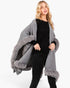 Beach Rose Co. grey knit cape with plush faux fur trim and front clasp closure worn by a blonde model