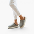 Beach Rose Co. Paula plush-lined grey slippers with thick non-slip soles worn with white trousers.