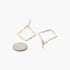 Beach Rose Co. gold-tone kite-shaped earrings with a hammered texture, shown next to a coin for size reference.