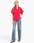 Beach Rose Co. hot pink blouse with smocked stand collar, lace trim, and voluminous sleeves worn with blue jeans.